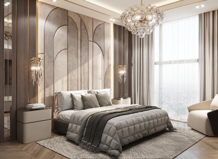 A plush double bed with a modern light fixture hanging overhead, panelled quilted walls, and neutral interior decor with sunlight streaming in from a large window