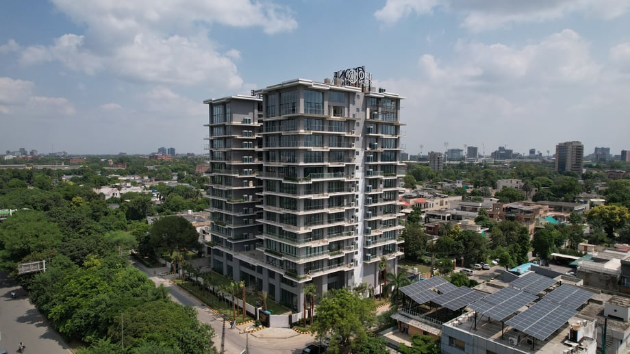 One Canal Road standing tall amidst Lahore's dense greenery beneath a blue sky speckled with clouds