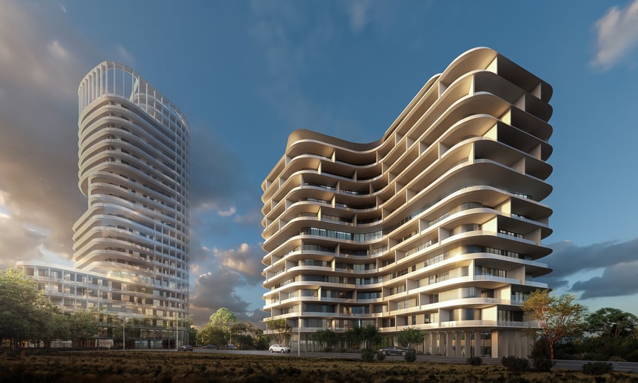 Two luxury apartment building structures stand side by side by a road against a bright blue sky, with greenery visible in the background