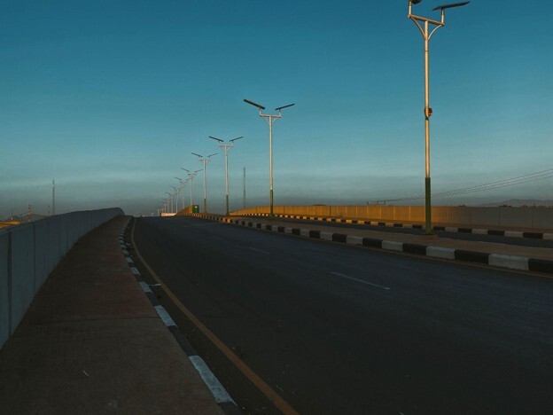 A smooth stretch of road with streetlights in between under a clear blue sky