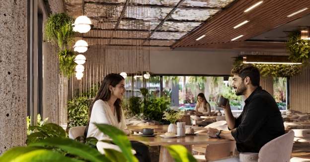 People enjoying a modern café at Diyar, a wellness community by One Homes in Islamabad, surrounded by indoor greenery and garden views