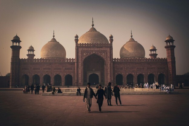 A group of people stand in front of the grand Badshahi Mosque in Lahore