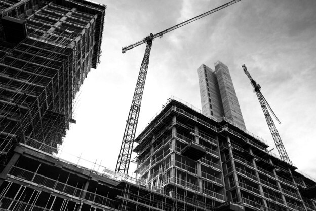 A building under construction with two cranes standing tall beside it