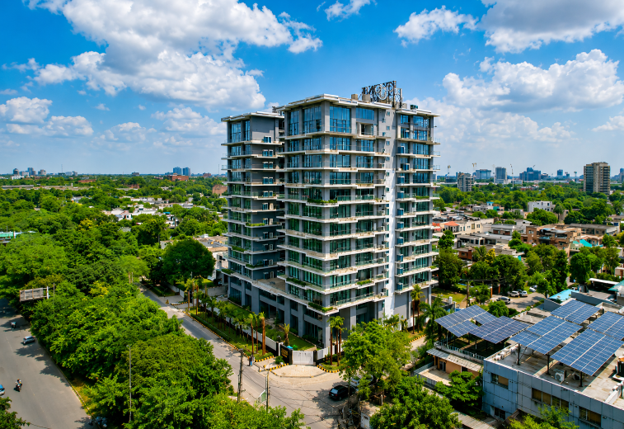 CGI view of One Canal Road rising above Lahore’s lush greenery under a clear blue sky, symbolising premium luxury apartments in Pakistan designed for overseas investors seeking lifestyle and stability.