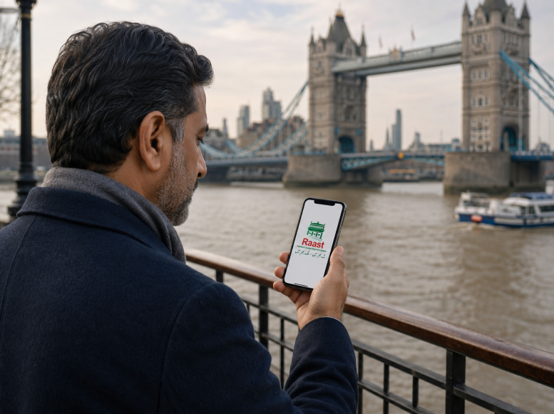 Middle-aged Pakistani man standing near Tower Bridge in London using the Raast app on his smartphone to send money to Pakistan.
