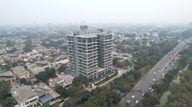 One Canal Road stands tall amidst trees on the inside of a main road, surrounded by other smaller buildings