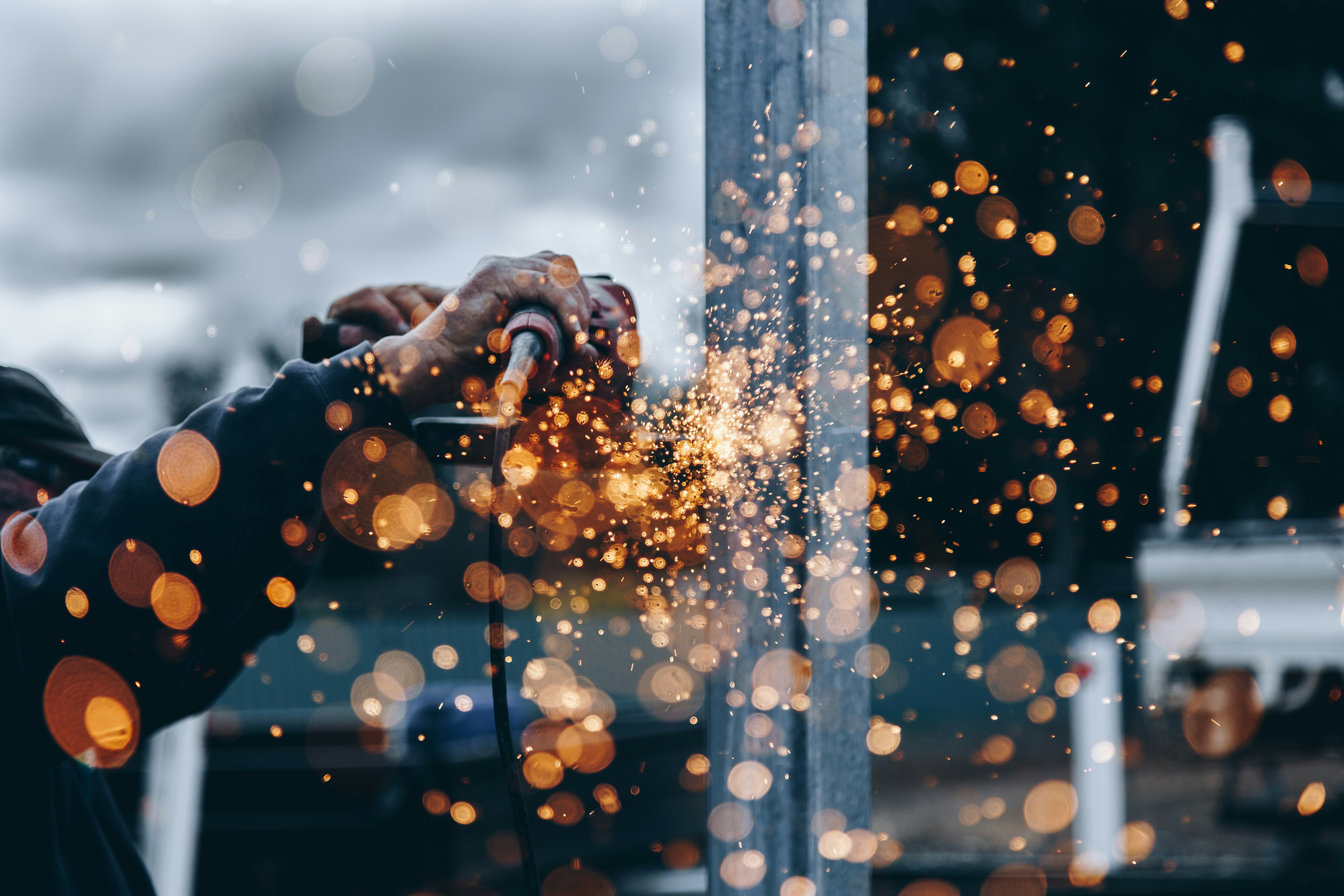 A close-up of a person welding with sparks flying towards the viewer