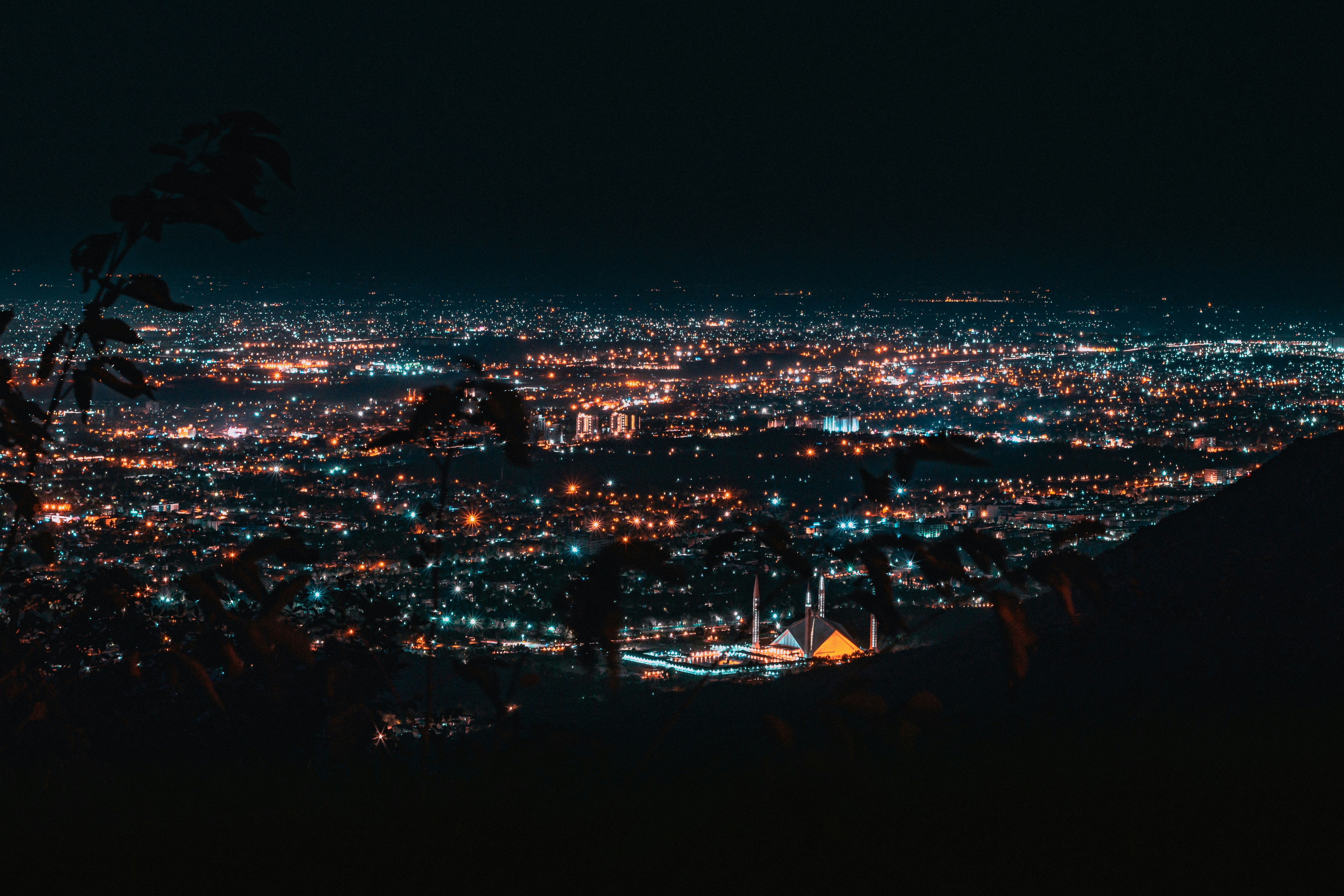 An image from an elevated angle showing Islamabad down below with the Faysal Mosque standing out amidst scattered lights at night