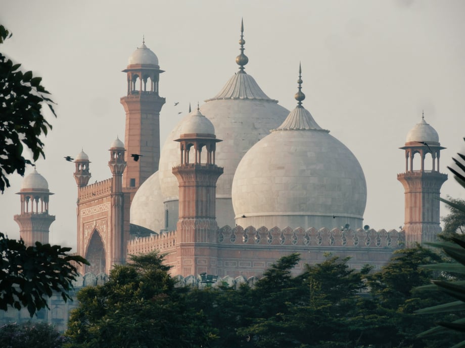 A close-up of the Badshahi Mosque with trees in the foreground