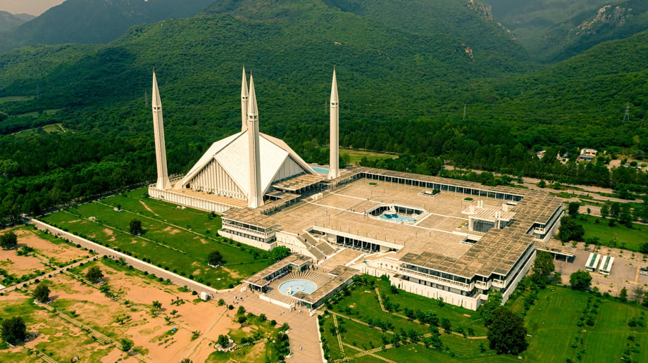 Wide shot of Islamabad’s Faisal Mosque framed by greenery and distant mountains, symbolising the city’s blend of cultural heritage and natural surroundings, and its appeal for planned property investment in Pakistan.