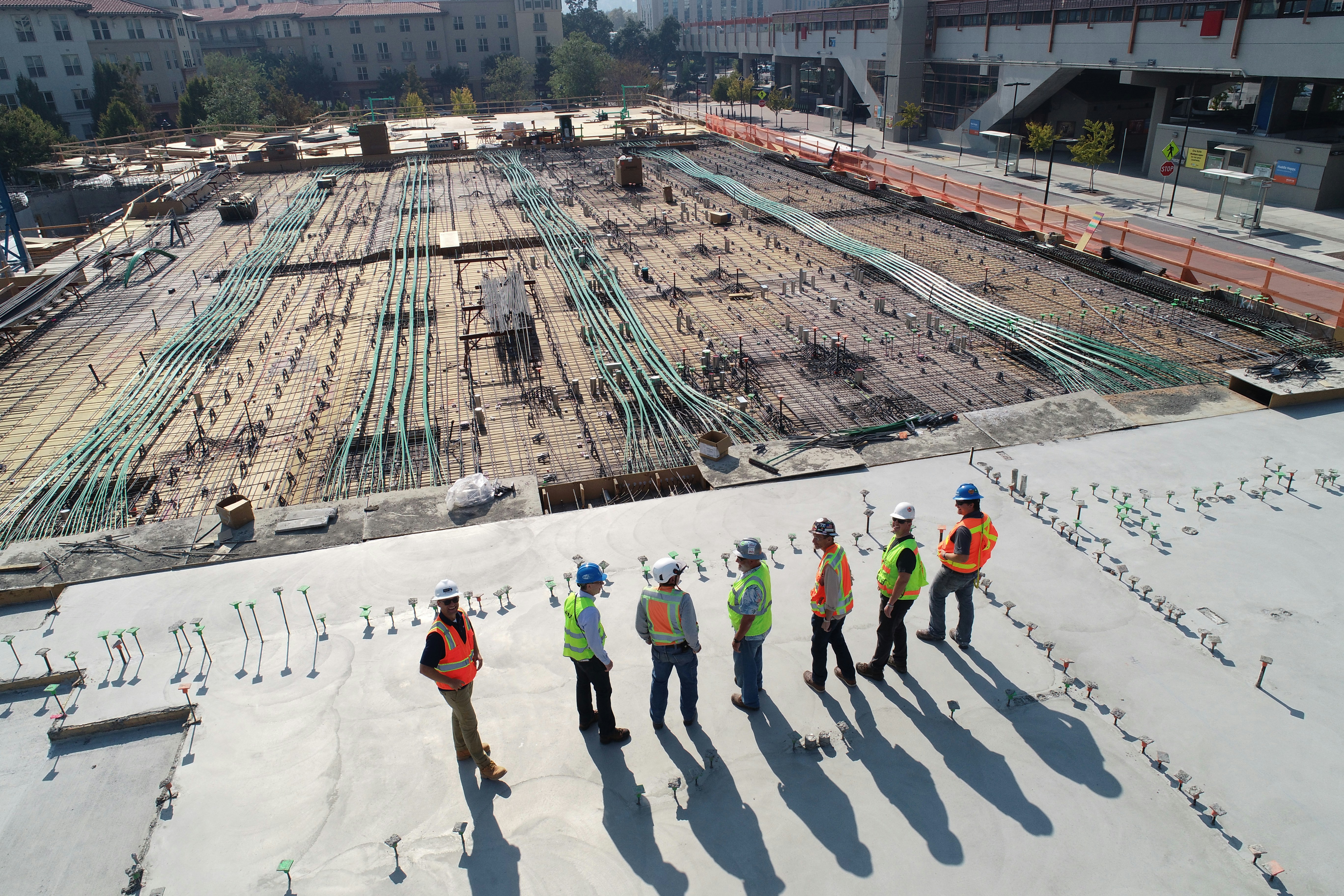 A group of construction workers stand together in safety gear at a site where the foundation of a building is in process