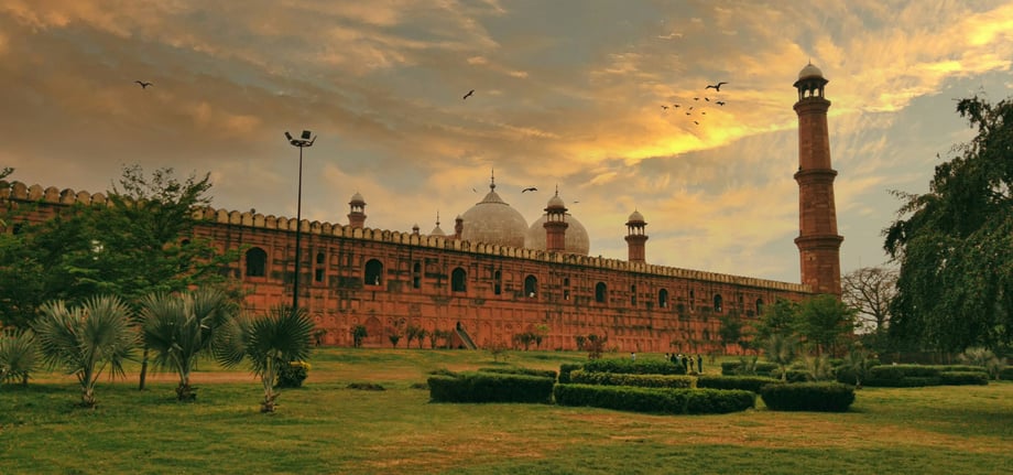 The Badshahi Mosque in Lahore is pictured against a glorious sky and surrounded by lush gardens and foliage