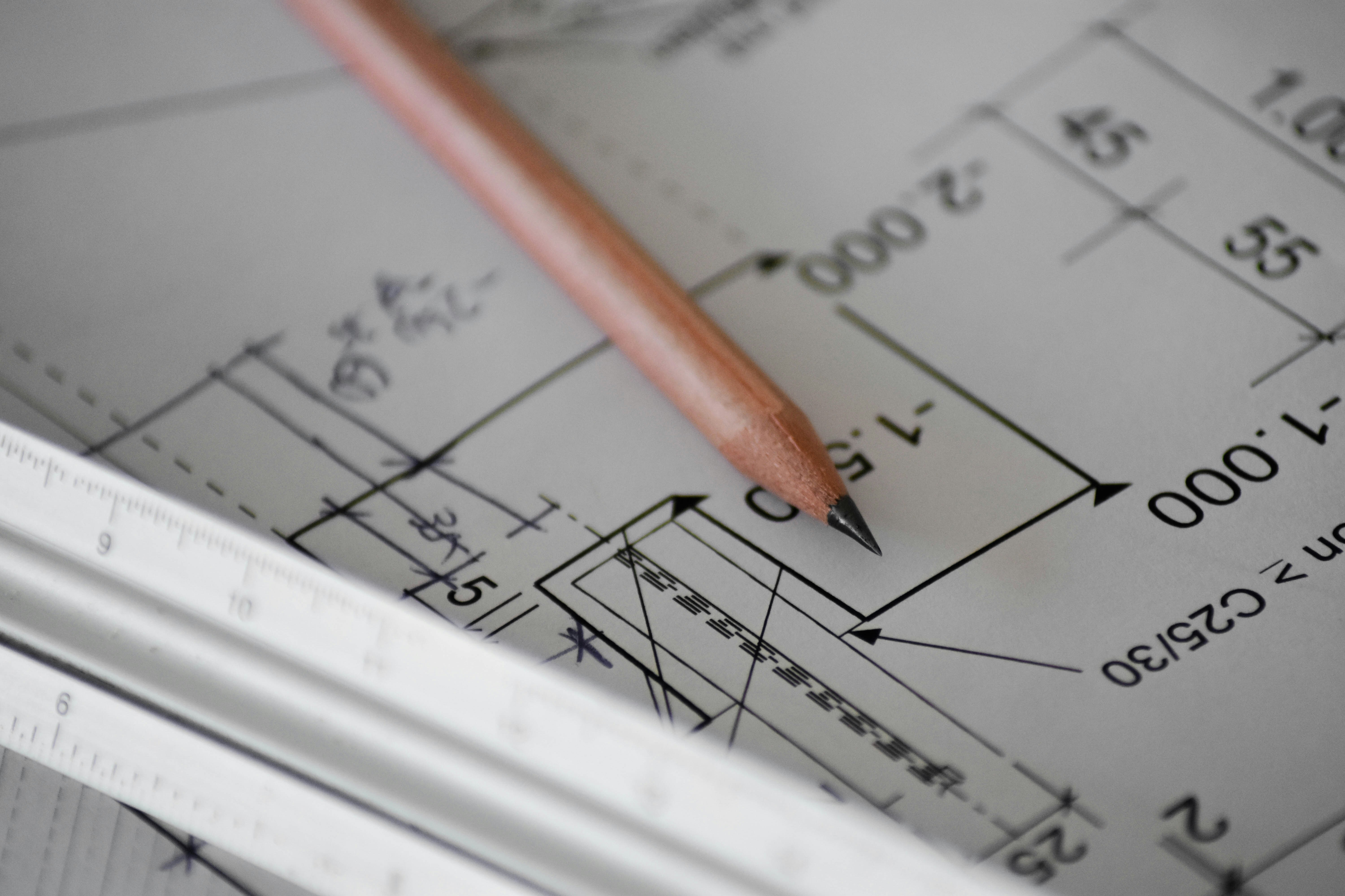 A close-up of a blueprint with a pencil and ruler